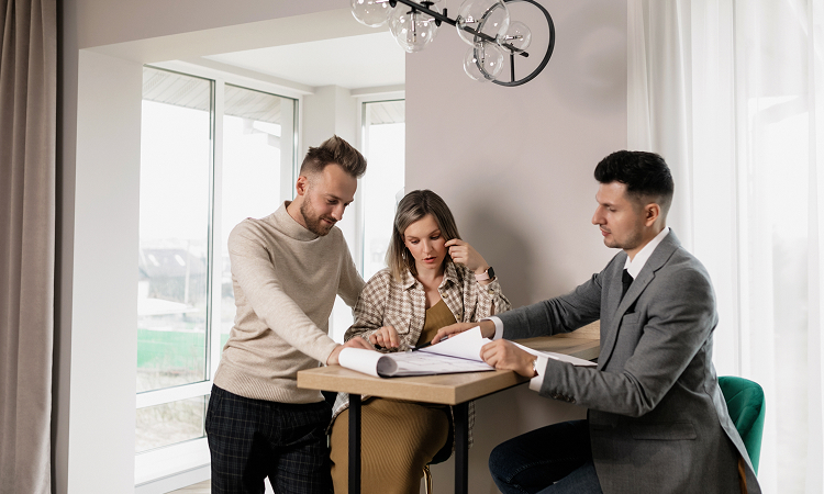 A professional real estate agent reviewing a contract with a client in a bright office, symbolising trust, regulation, and transparency in property transactions.